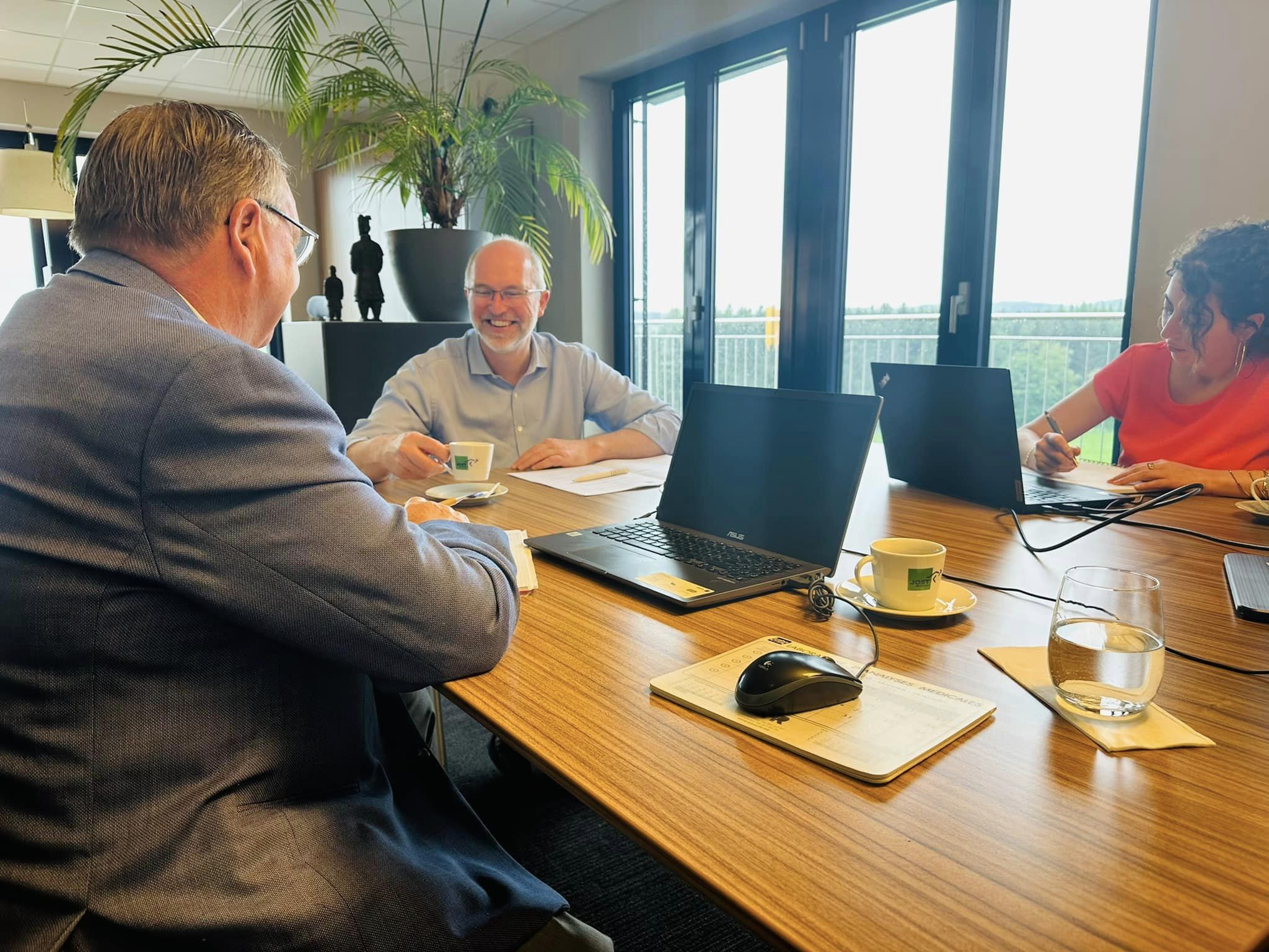 Three employees of the Jost transport company in a meeting discussing and taking notes.