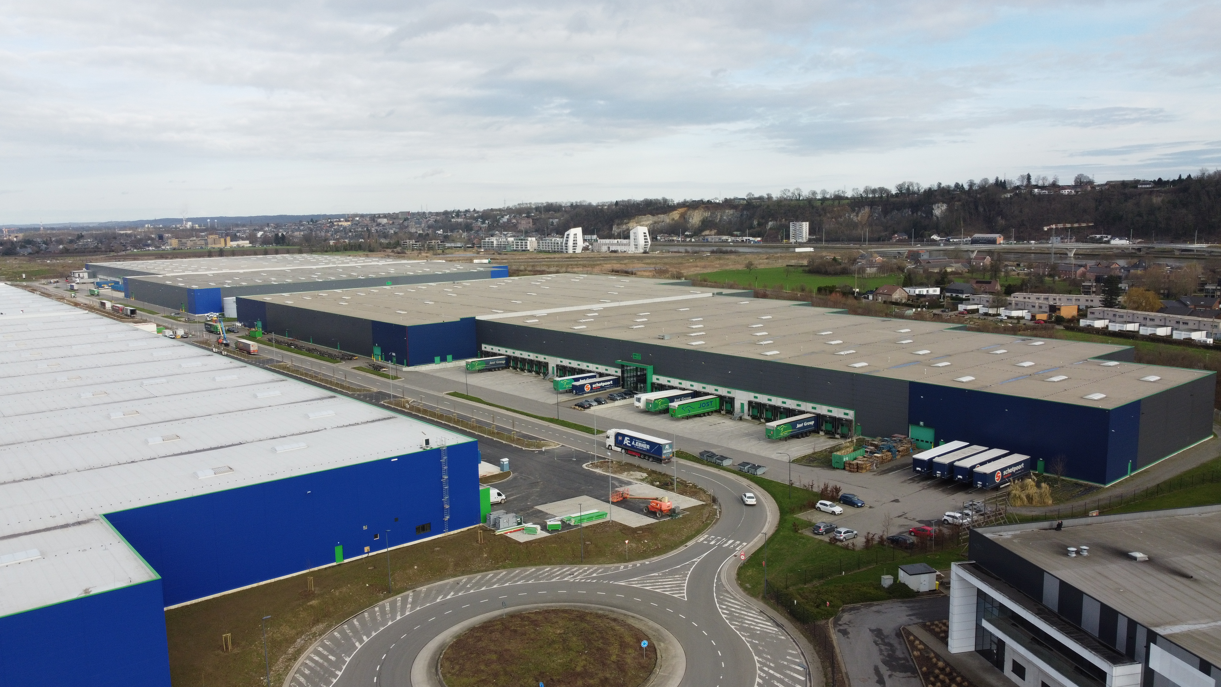 A logistics hub with numerous access doors and vans parked in front.