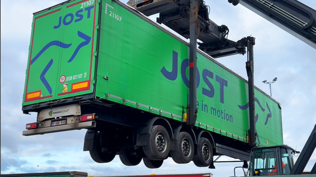 Une remorque train verte de chez JOST soulevée par un stacker pour être posée sur le train