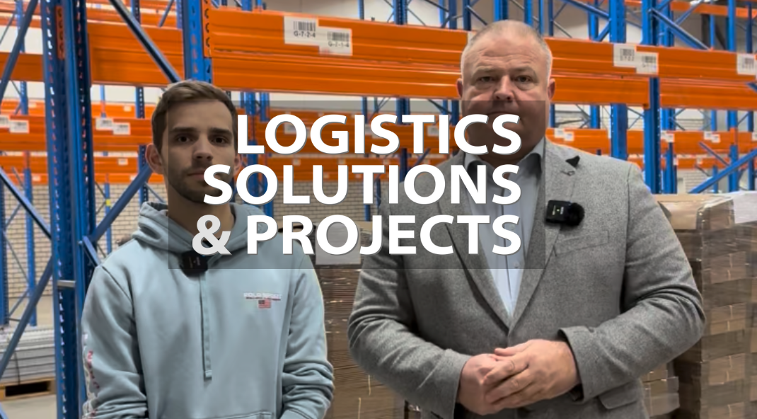 Two men standing in front of orange racks with the Logistics Solutions & Projects logo
